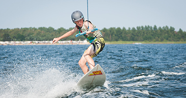 Zawodnik płynie za motorówka uprawiając wakeboarding